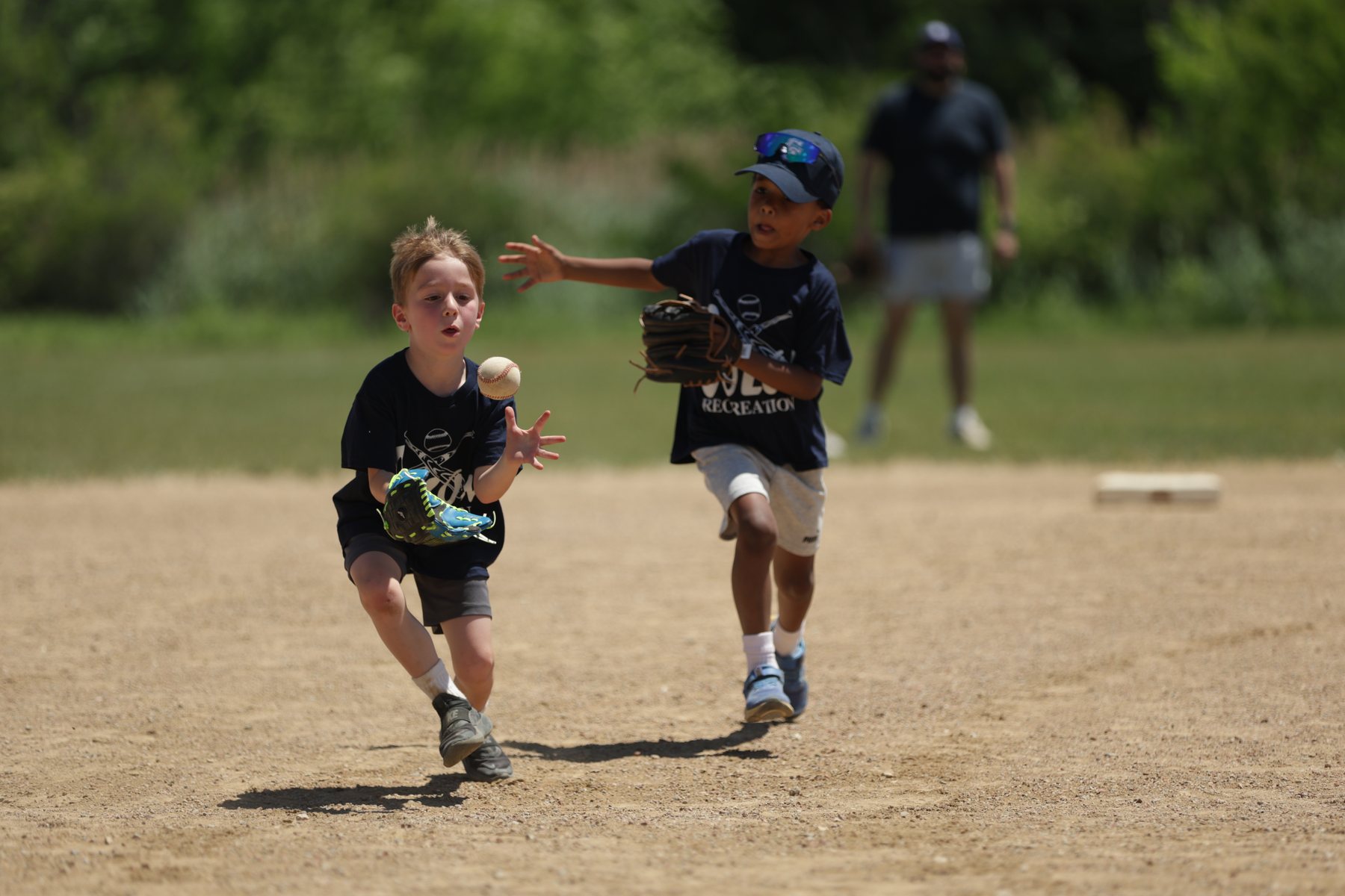 Two youth baseball players running together on the field.