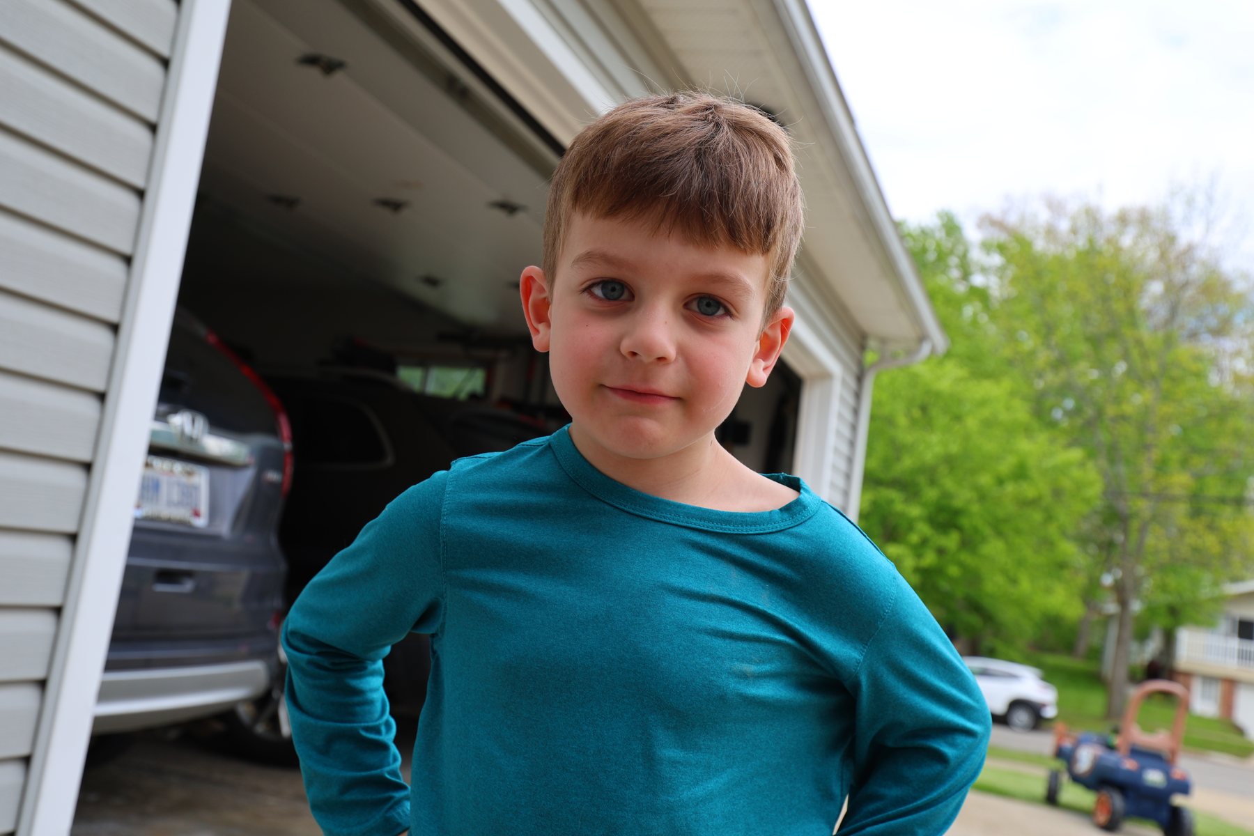 Confident young boy standing in a driveway.