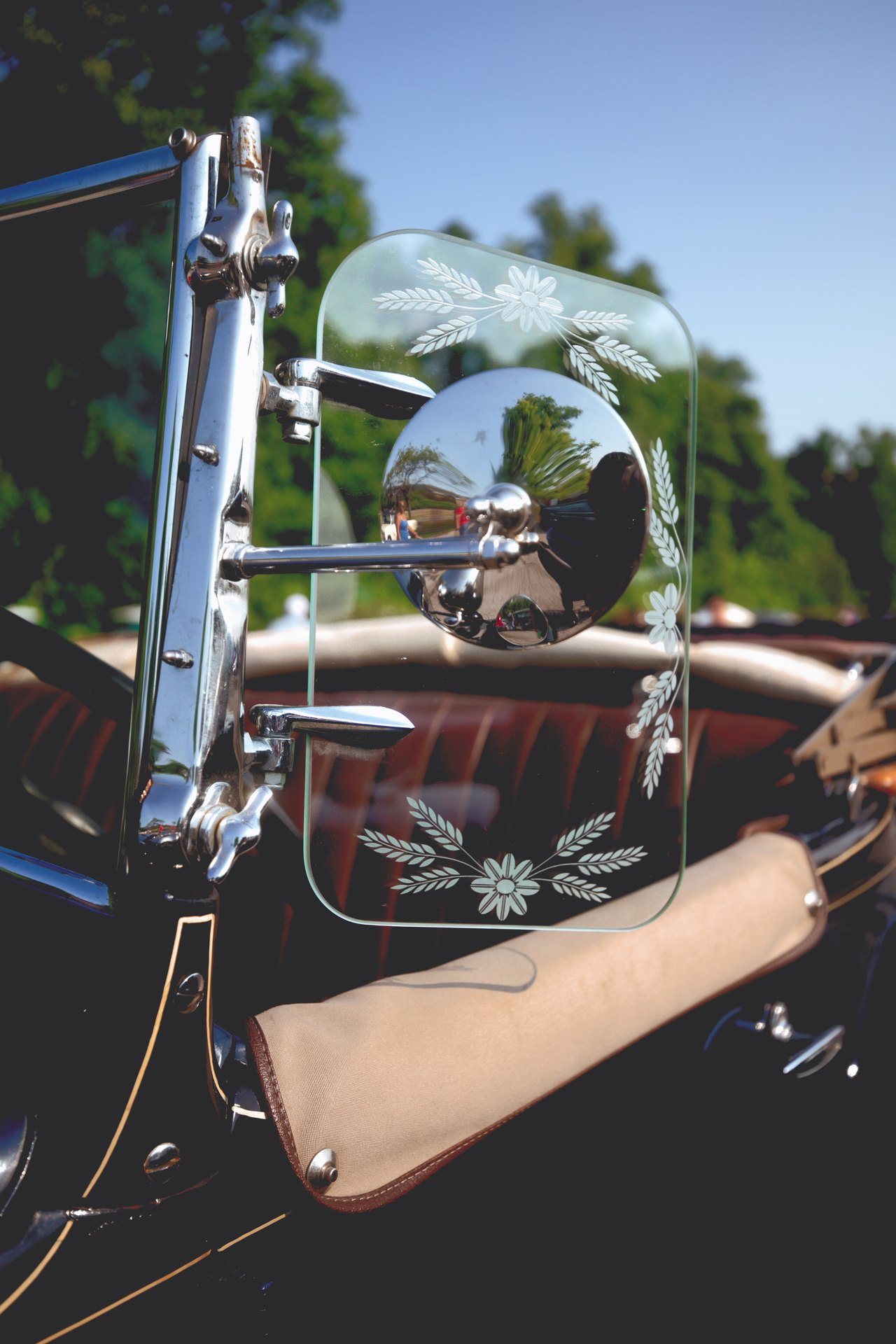 Etched glass and chrome mirror detail on a vintage car.