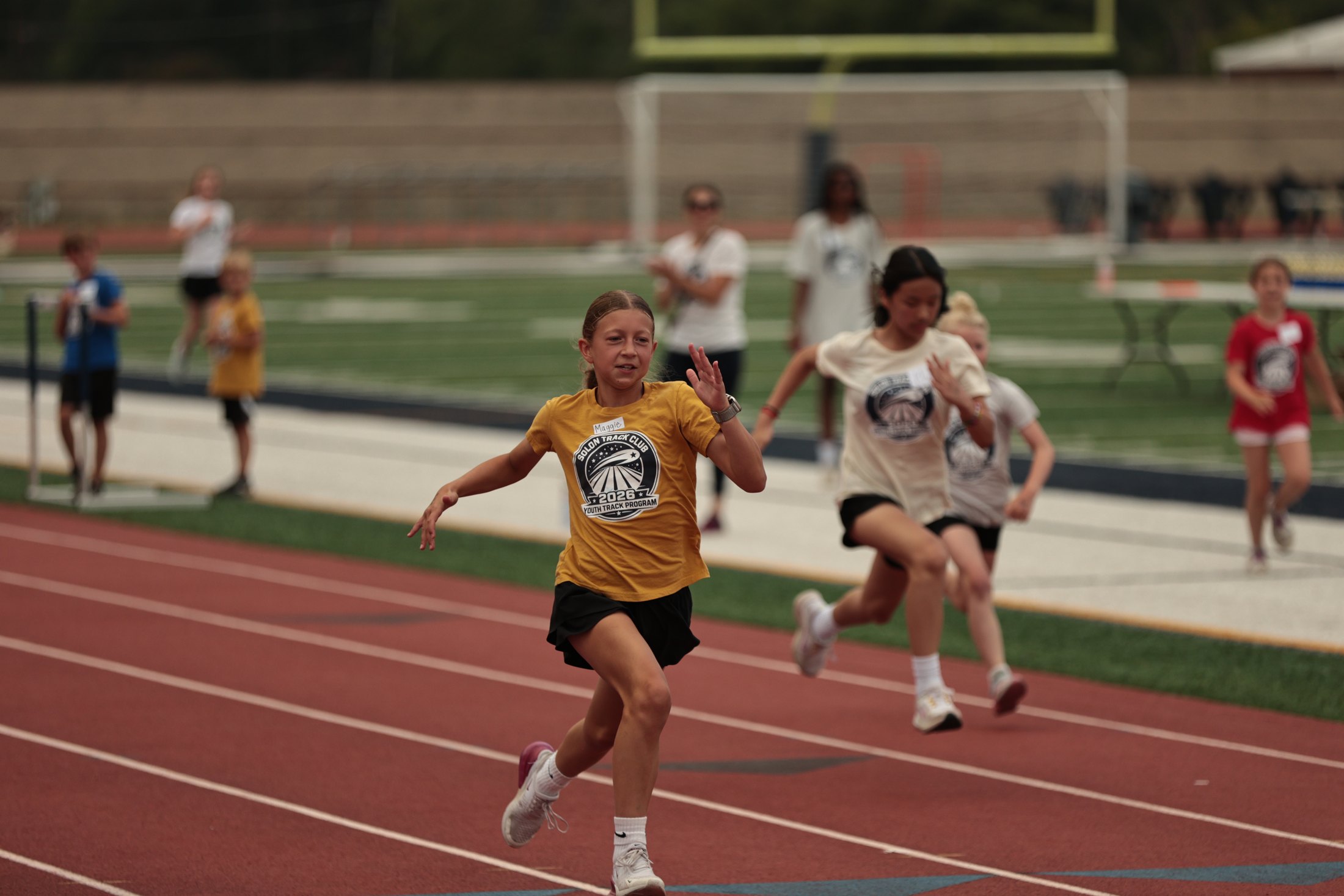 Young runners moving around a track.