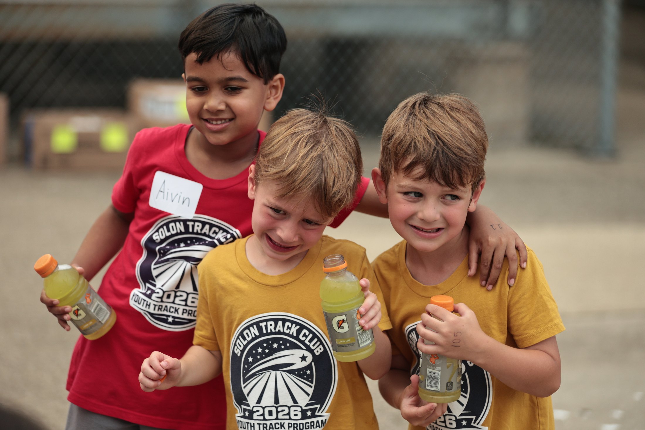 Three young track participants smiling together.